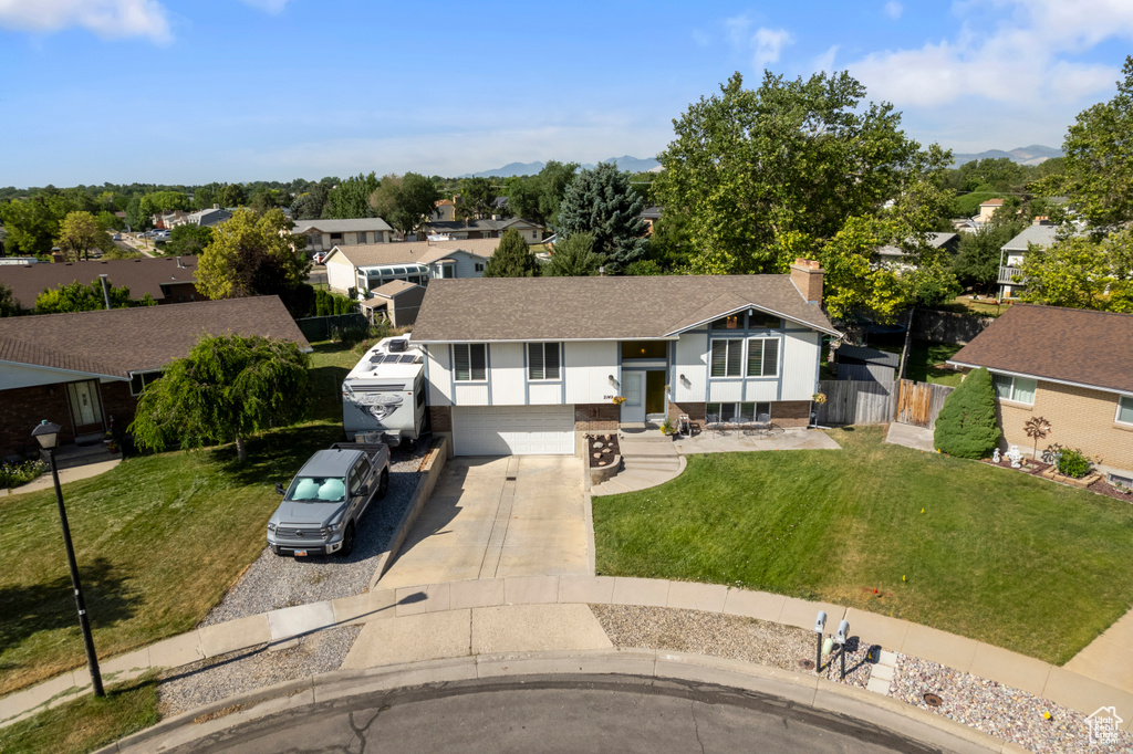 Split foyer home featuring driveway, a residential view, roof with shingles, a chimney, and an attached garage