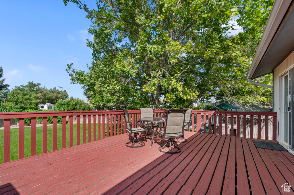 Wooden terrace featuring outdoor dining space and a lawn