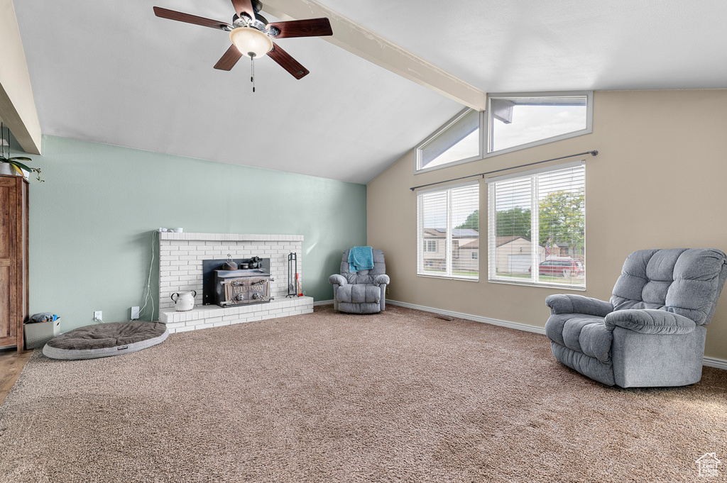 Sitting room featuring a wood stove, ceiling fan, and carpet flooring