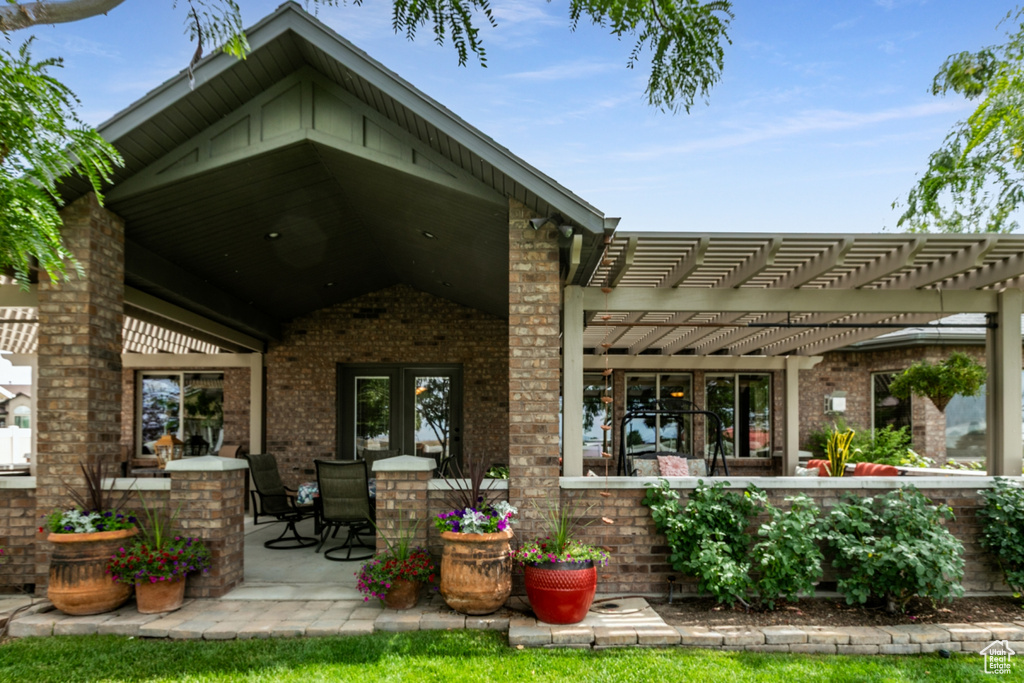 Back of property featuring brick siding, a pergola, and a patio