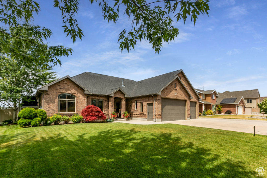View of front facade with brick siding, a garage, a front lawn, and driveway