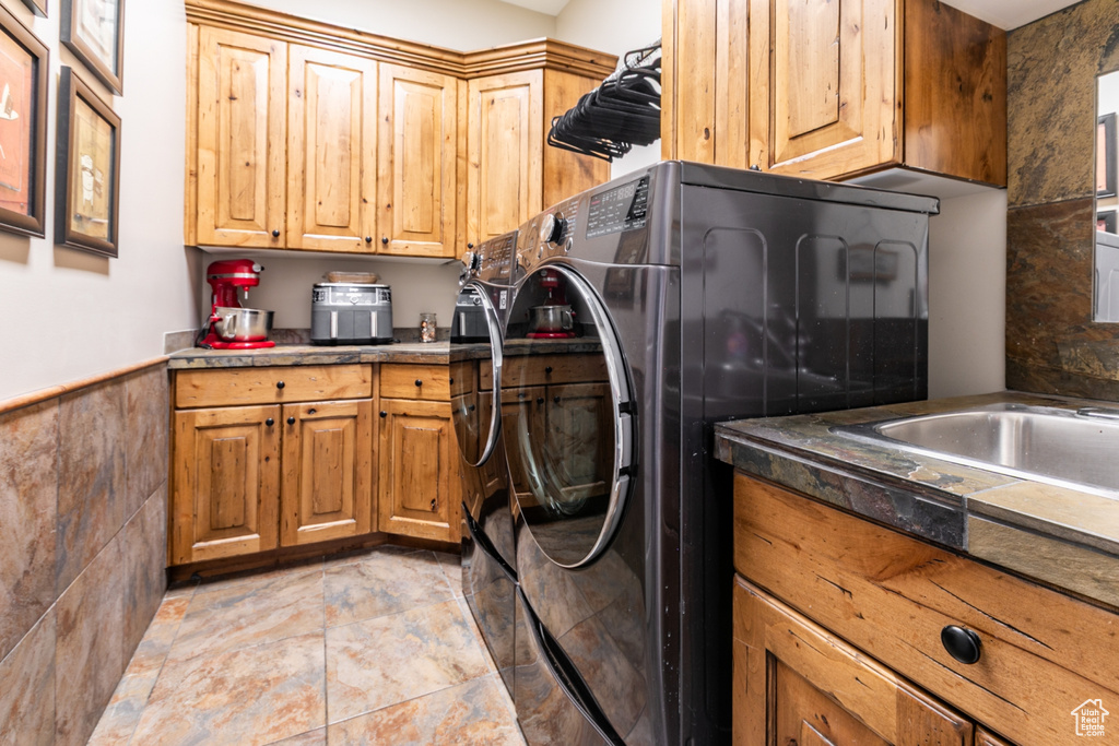 Laundry room with cabinet space, washing machine and dryer, a wainscoted wall, and tile walls