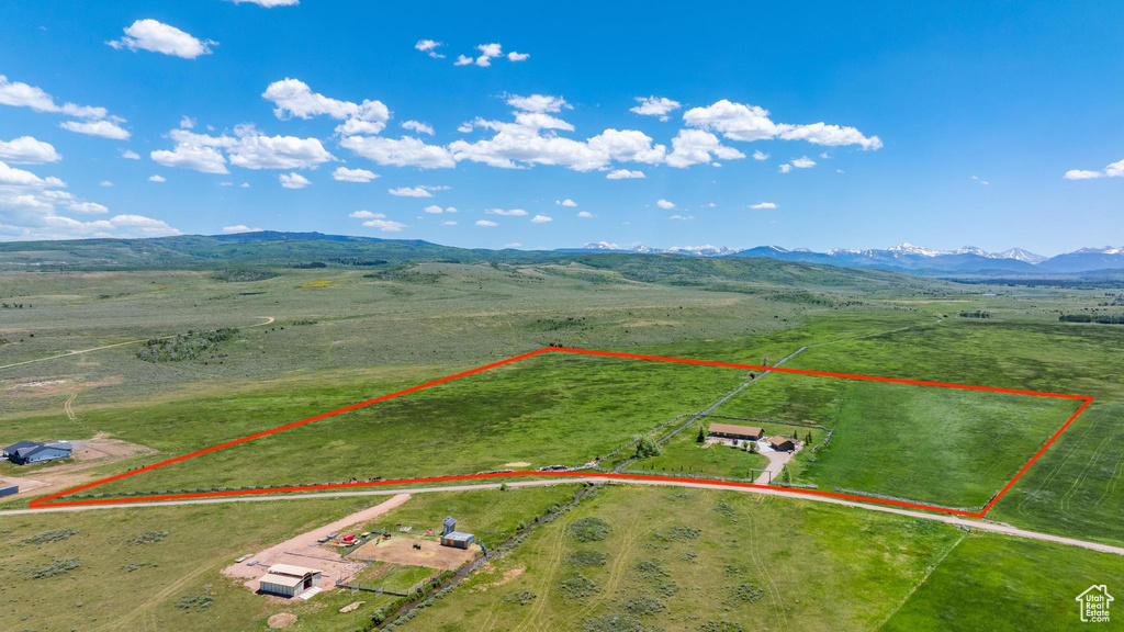 Aerial view of sparsely populated area with property parcel outlined and a mountainous background