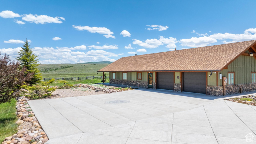 View of front of house with a garage, board and batten siding, concrete driveway, and stone siding