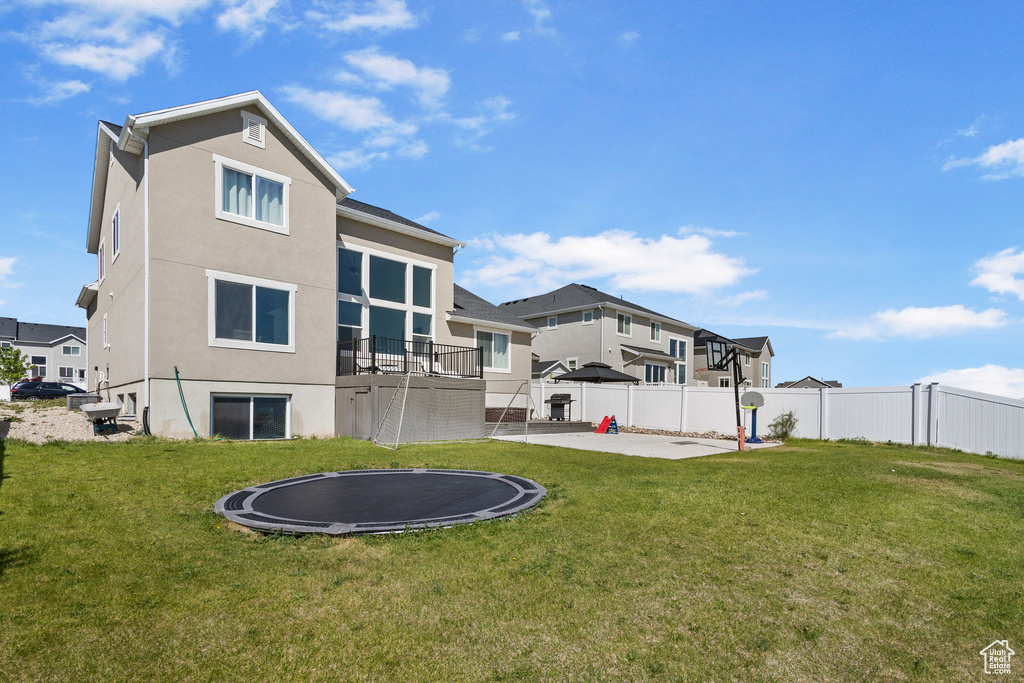 Rear view of property with a trampoline, stucco siding, a patio area, and a residential view