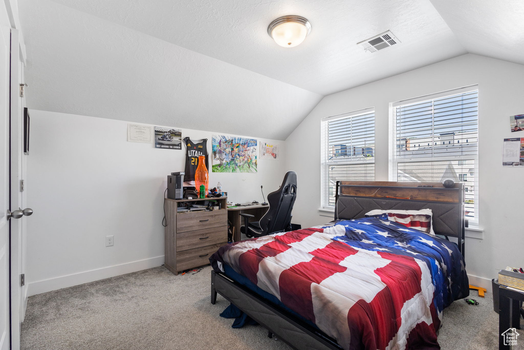 Bedroom with lofted ceiling and light carpet