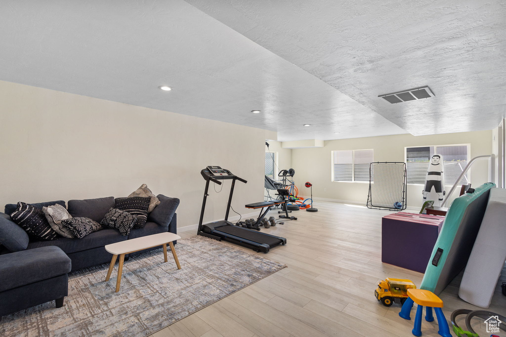Workout room with wood finished floors and recessed lighting