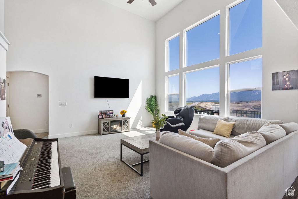 Carpeted living room featuring a towering ceiling, arched walkways, and a ceiling fan