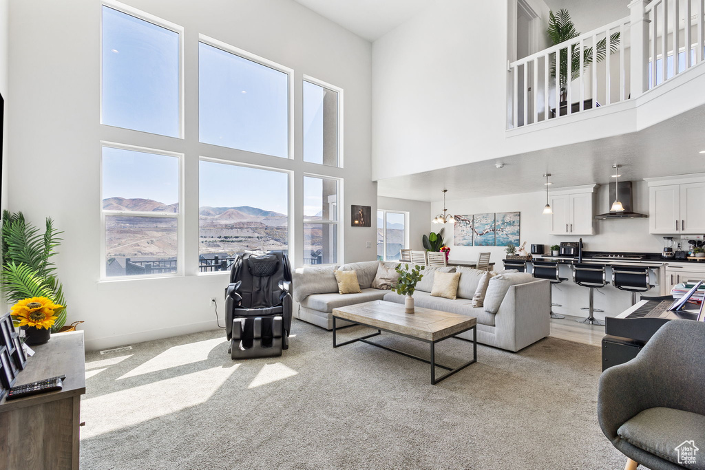 Living room featuring a towering ceiling, light carpet, a chandelier, and a mountain view