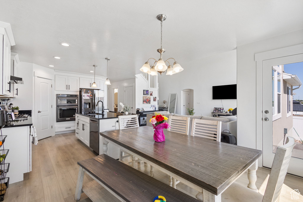 Dining room with light wood-style floors, recessed lighting, a chandelier, and arched walkways