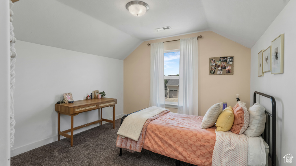 Bedroom featuring lofted ceiling and dark colored carpet
