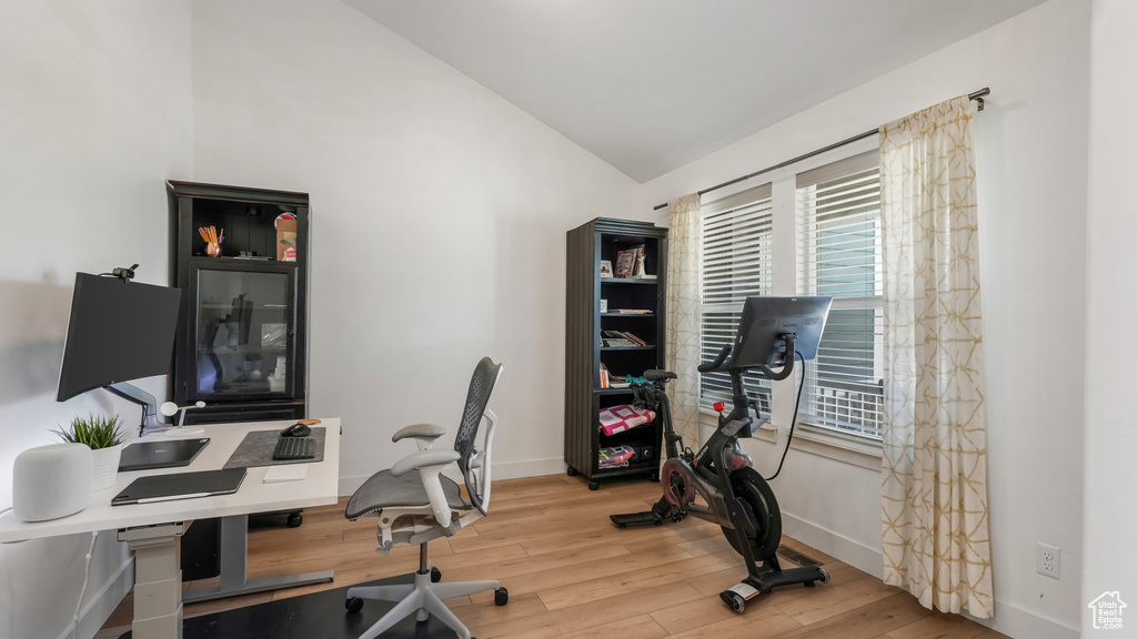 Home office with lofted ceiling and wood finished floors