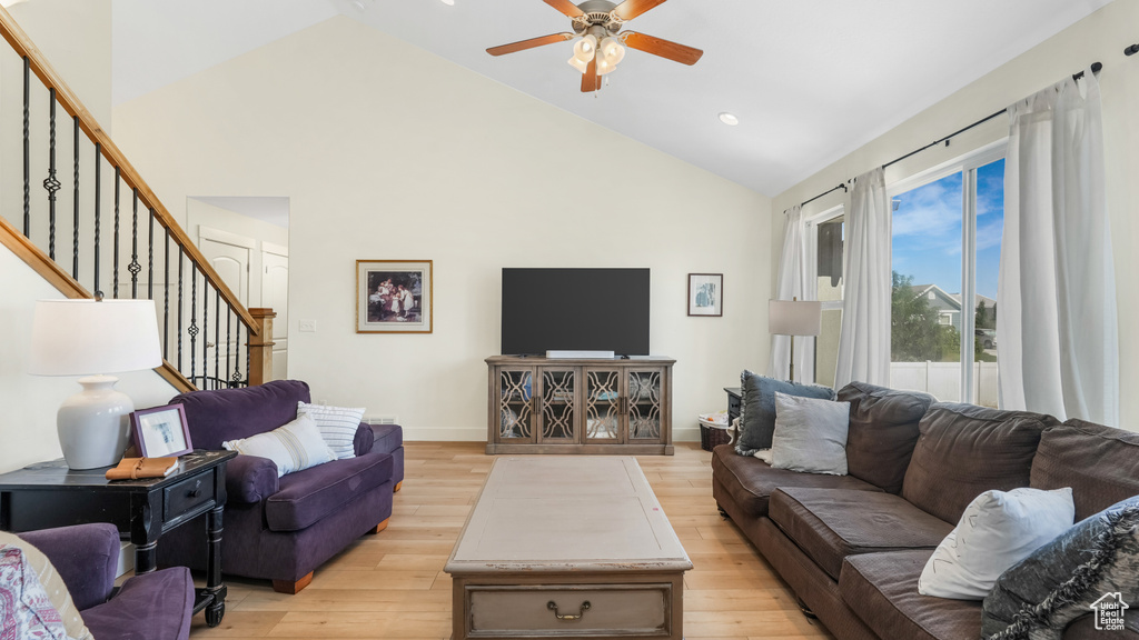 Living room with high vaulted ceiling, ceiling fan, stairway, light wood finished floors, and recessed lighting
