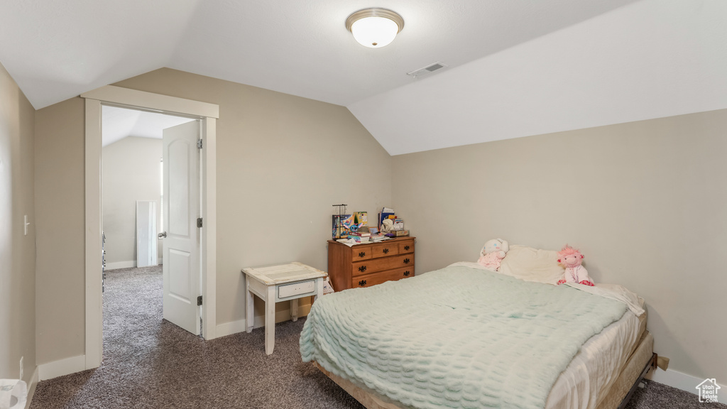 Carpeted bedroom with vaulted ceiling and baseboards