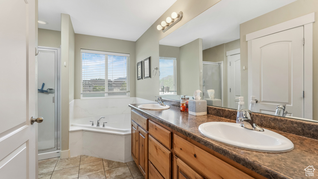 Bathroom with a shower stall, double vanity, a bath, and tile patterned floors