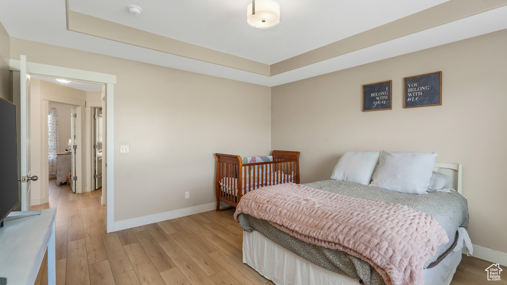 Bedroom featuring light wood-style floors and a raised ceiling