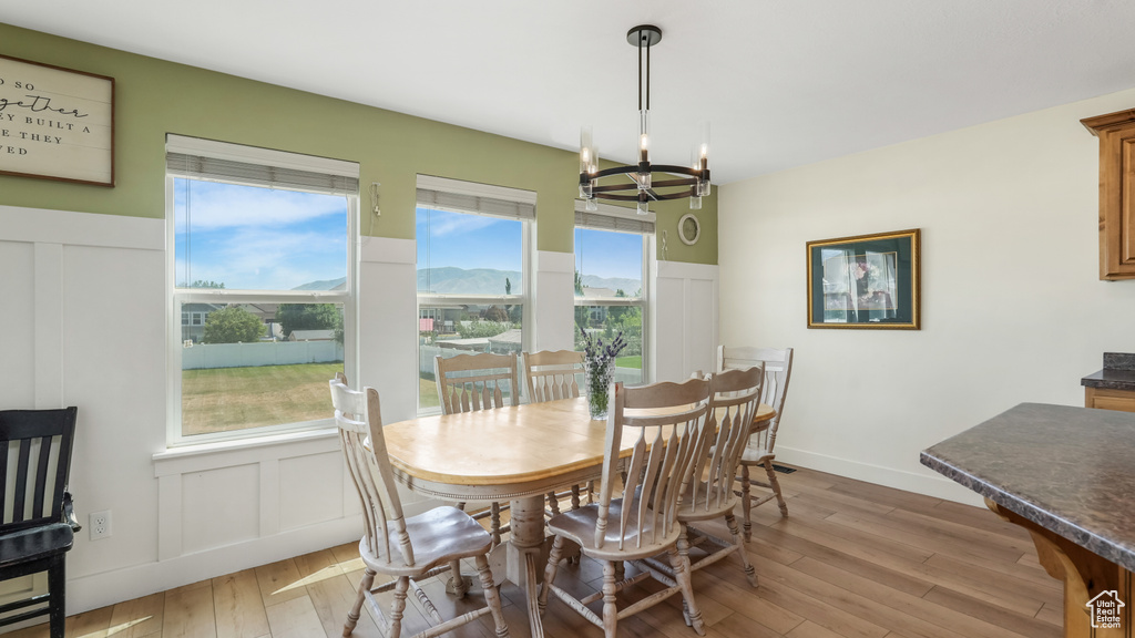 Dining room with a decorative wall, a chandelier, light wood-style floors, and a wainscoted wall