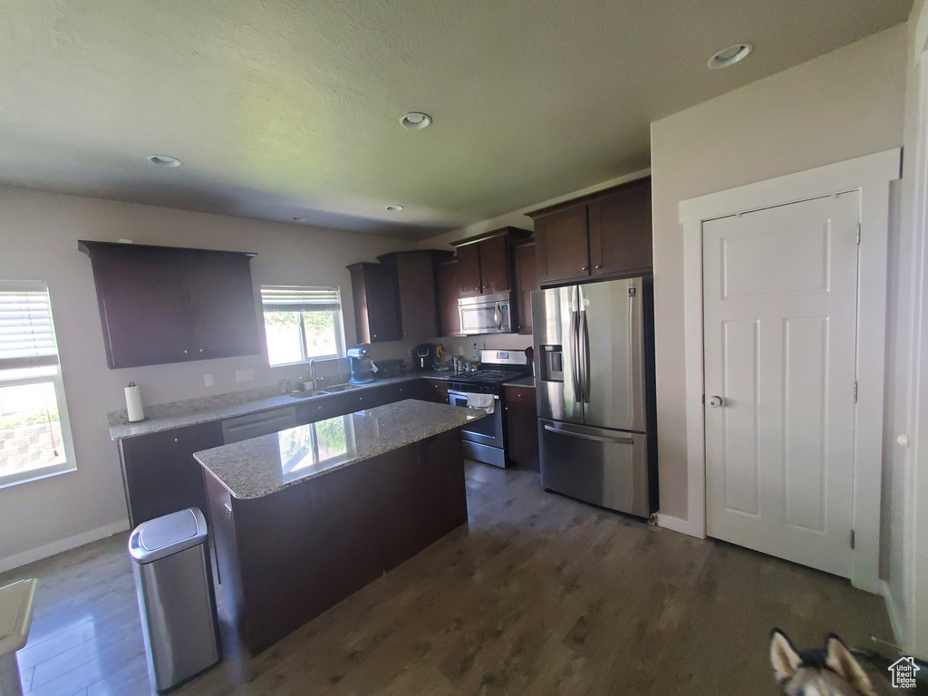 Kitchen featuring stainless steel appliances, a kitchen island, dark wood finished floors, dark brown cabinets, and recessed lighting