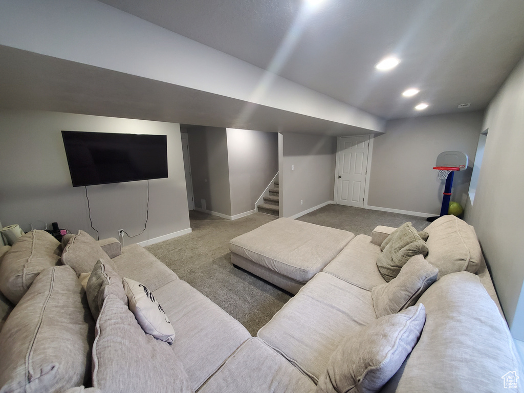 Carpeted living area with stairs and recessed lighting