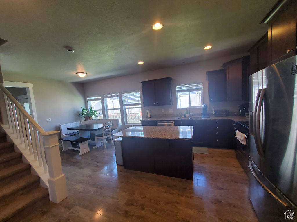 Kitchen featuring stainless steel appliances, a kitchen island, recessed lighting, dark wood-style flooring, and light stone counters