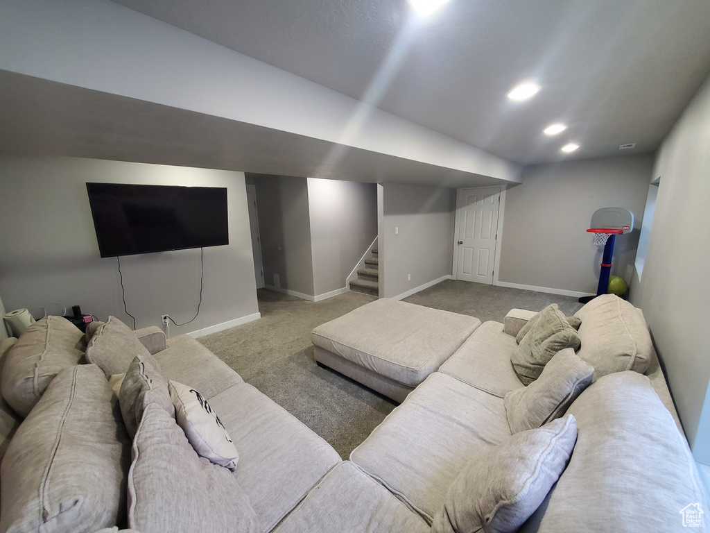 Carpeted living room with stairs and recessed lighting