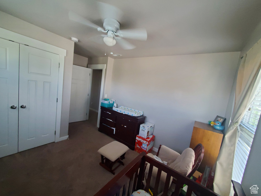 Carpeted bedroom featuring ceiling fan and a closet