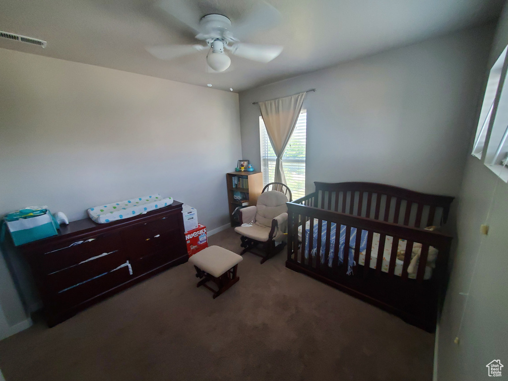 Bedroom with a crib, carpet floors, and a ceiling fan