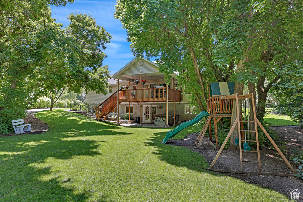 View of jungle gym featuring a yard, stairs, and a wooden deck