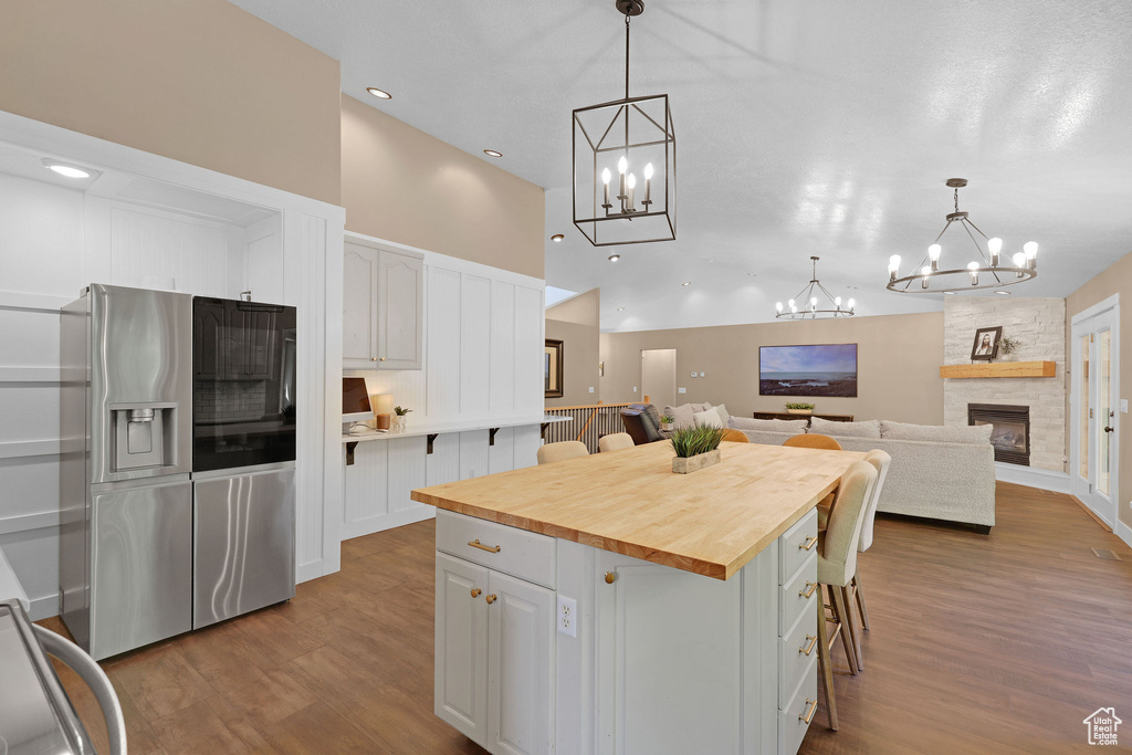 Kitchen featuring a chandelier, wood counters, wood finished floors, white cabinets, and high vaulted ceiling