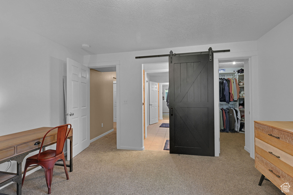 Home office with light colored carpet, a textured ceiling, and a barn door