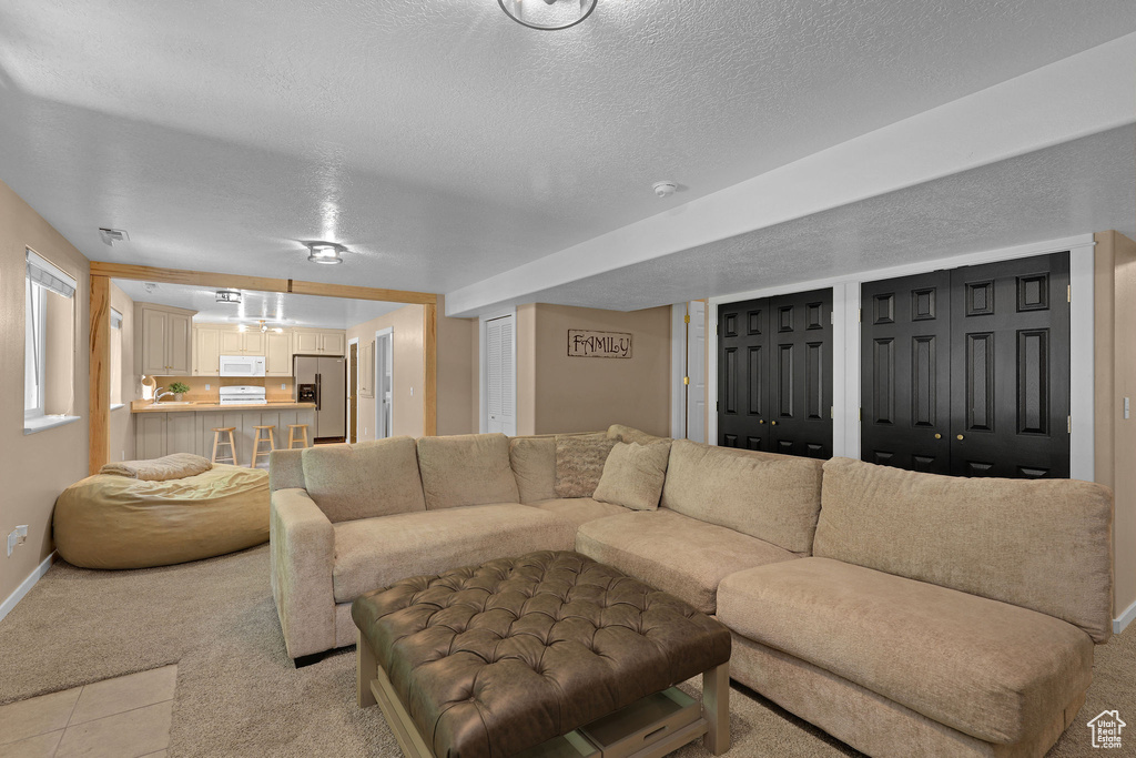 Living room featuring light carpet, a textured ceiling, and light tile patterned flooring