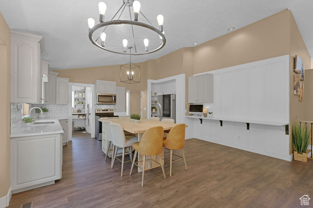 Dining space featuring a chandelier, dark wood finished floors, and lofted ceiling