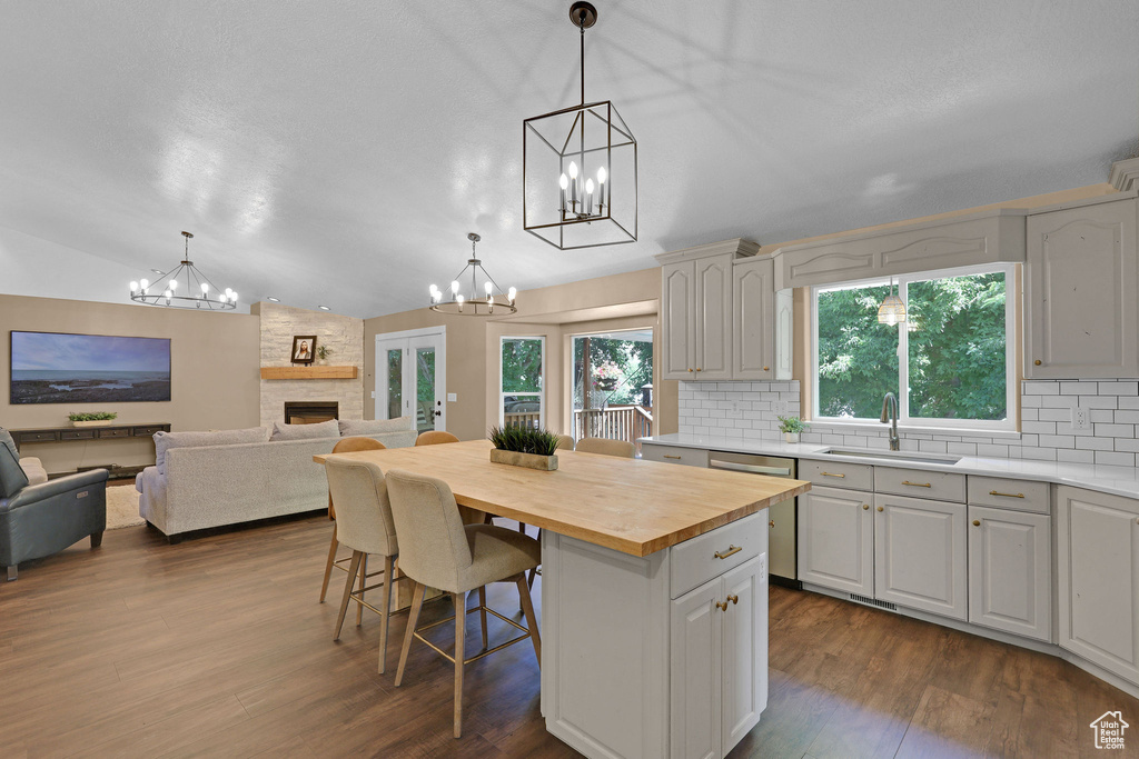 Kitchen featuring a chandelier, butcher block countertops, decorative backsplash, a kitchen island, and lofted ceiling