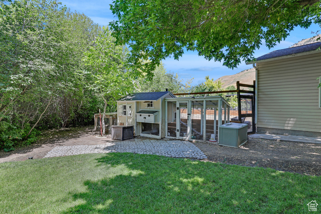 Rear view of house with exterior structure, a lawn, and an outbuilding