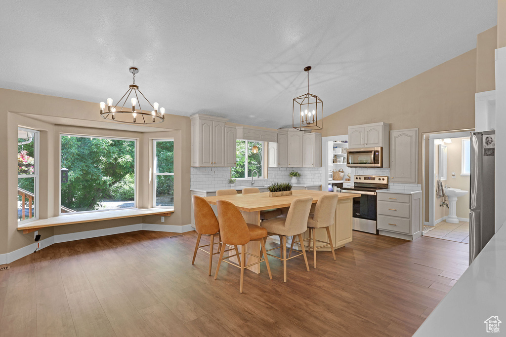 Dining space featuring a chandelier, wood finished floors, and lofted ceiling