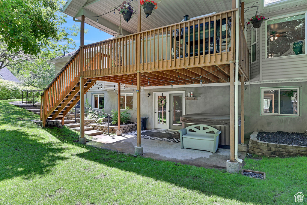 Back of house featuring a hot tub, a deck, a yard, a patio area, and stairs