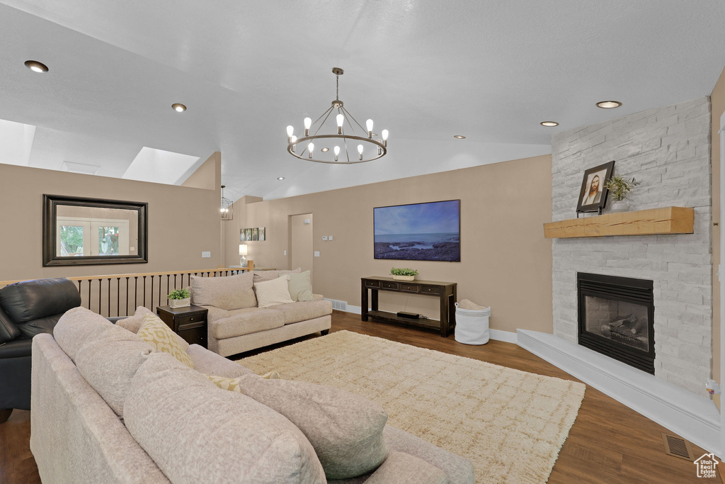 Living area featuring dark wood finished floors, a chandelier, lofted ceiling, a fireplace, and recessed lighting