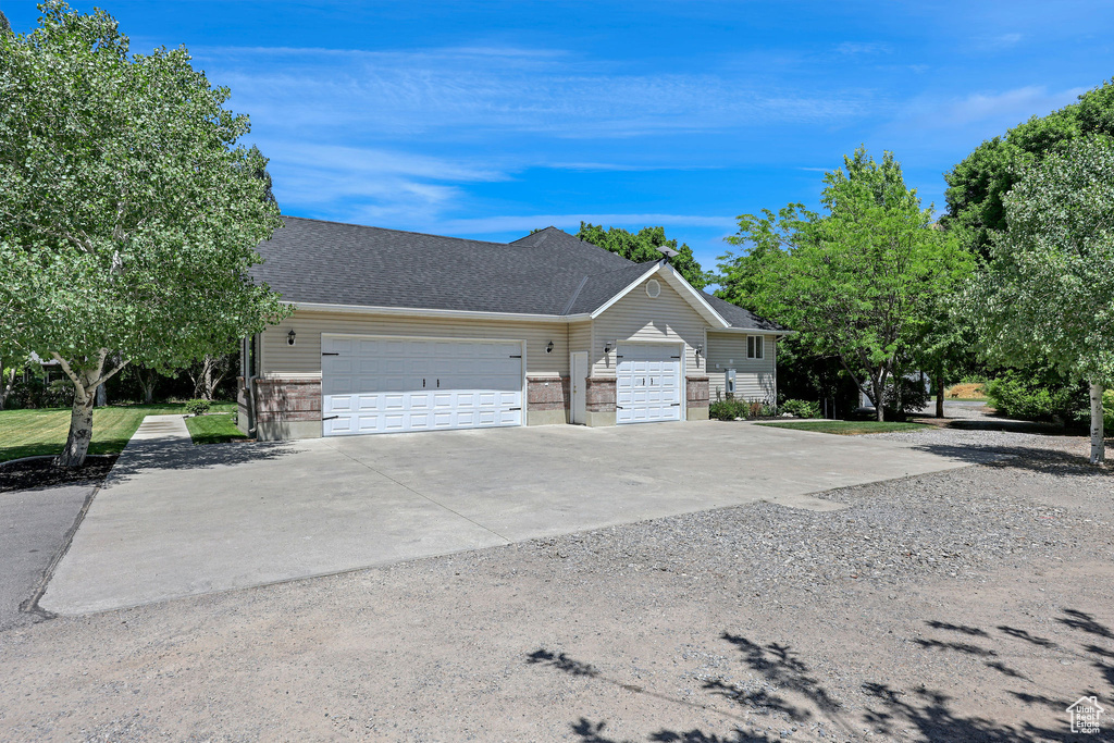 View of front facade featuring concrete driveway, an attached garage, and roof with shingles