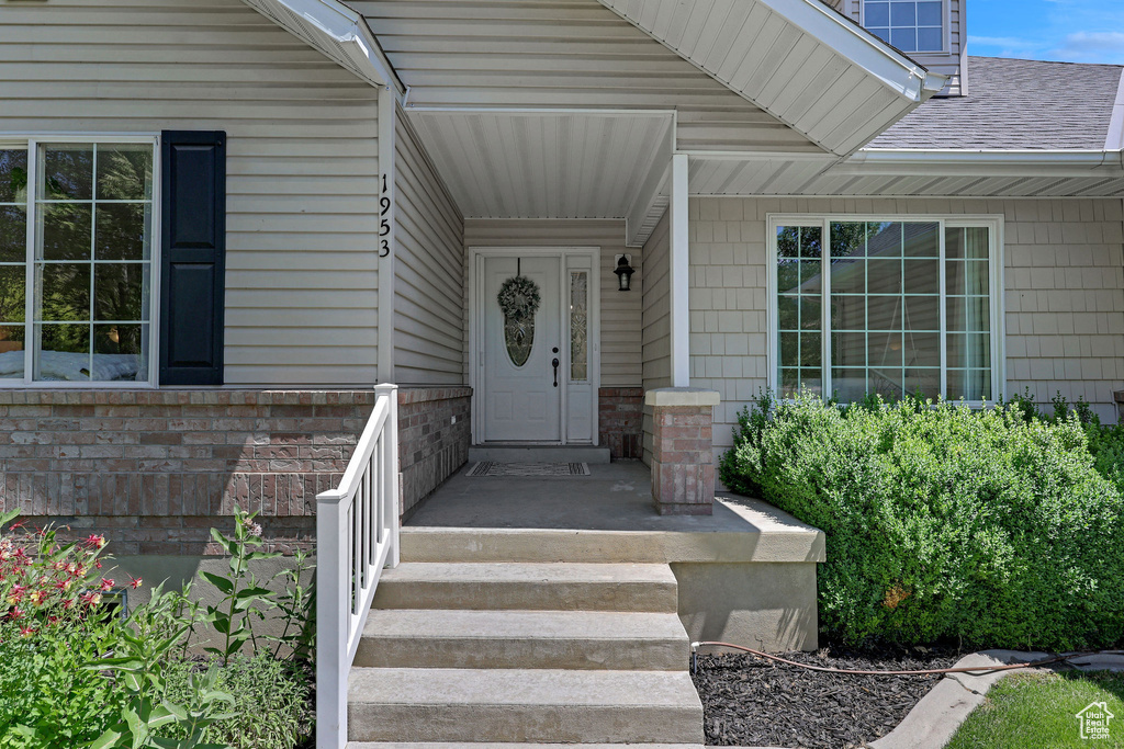 Doorway to property featuring roof with shingles