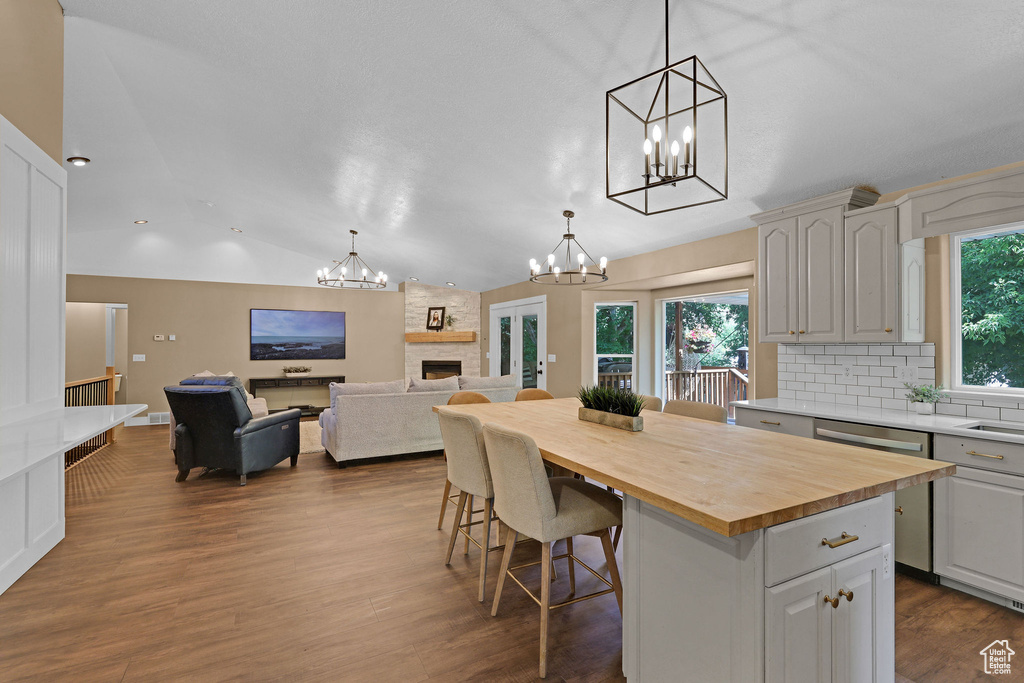 Kitchen featuring a chandelier, wood counters, vaulted ceiling, a kitchen island, and decorative backsplash