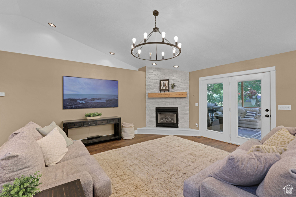 Living room with wood finished floors, a chandelier, vaulted ceiling, recessed lighting, and a fireplace