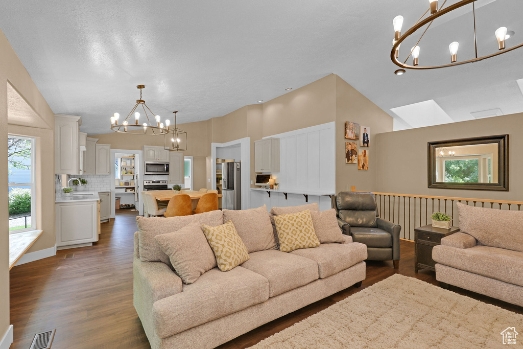 Living room with a chandelier, dark wood-type flooring, and vaulted ceiling