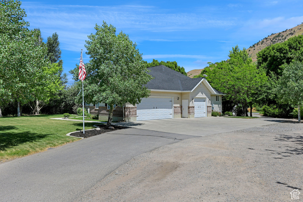 View of front facade featuring concrete driveway, a garage, a front yard, and a shingled roof
