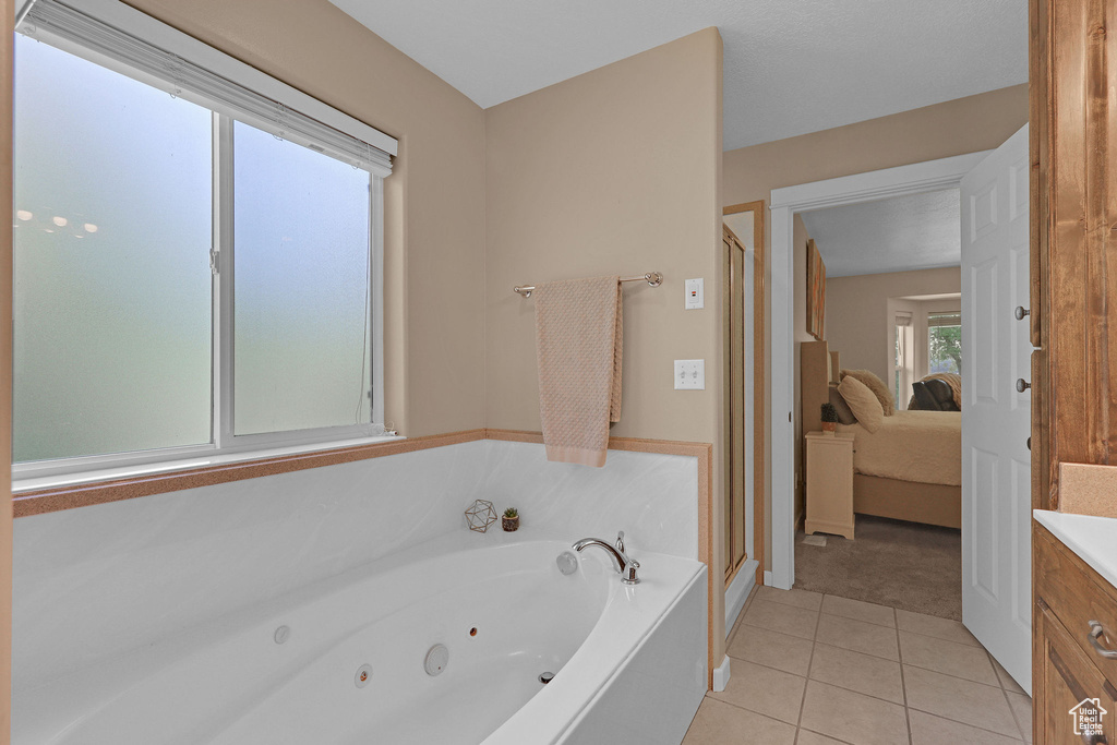 Bathroom featuring tile patterned floors, a jetted tub, a stall shower, connected bathroom, and vanity
