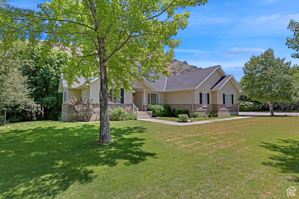 Ranch-style home with a front yard, brick siding, a chimney, and a shingled roof