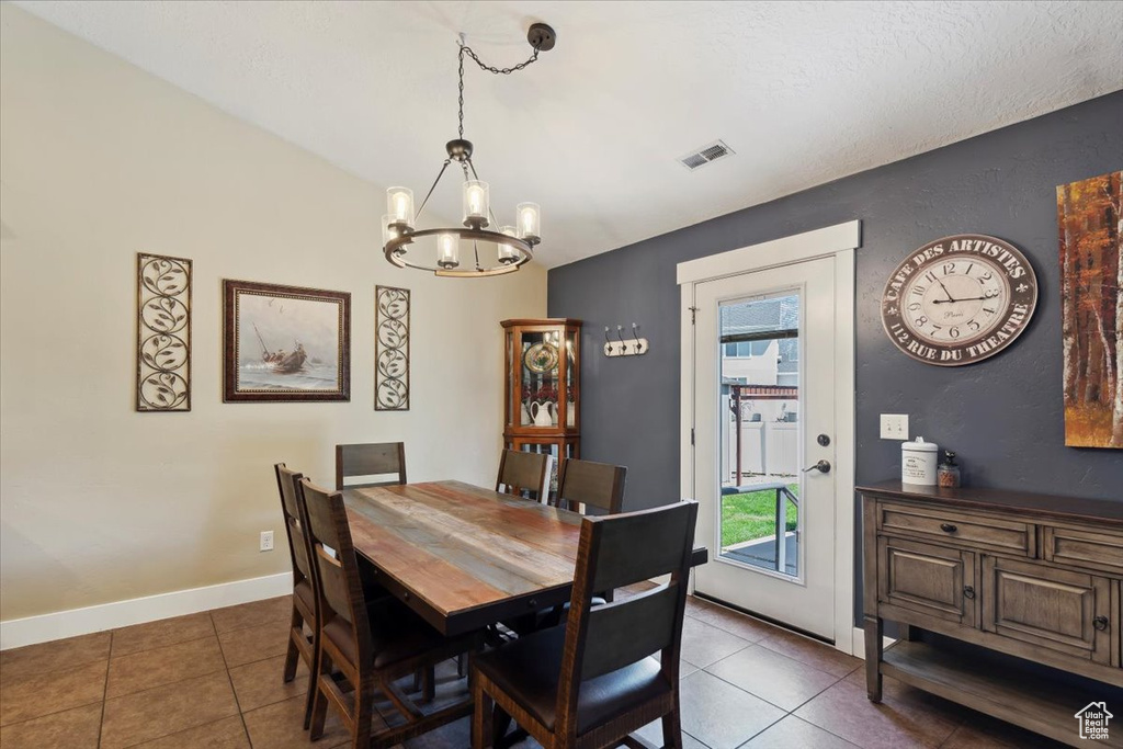 Tiled dining space featuring a chandelier and baseboards