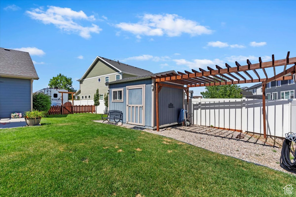Fenced backyard featuring a shed and a pergola