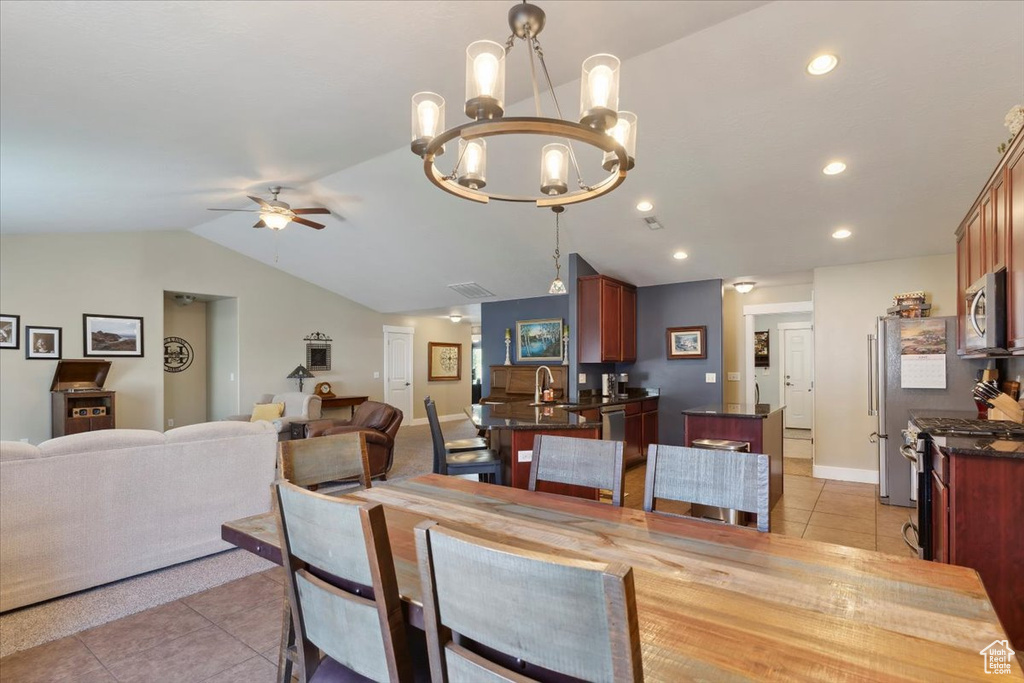Dining space with light tile patterned floors, lofted ceiling, ceiling fan, a chandelier, and recessed lighting