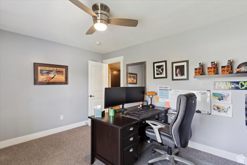 Carpeted home office with baseboards and a ceiling fan
