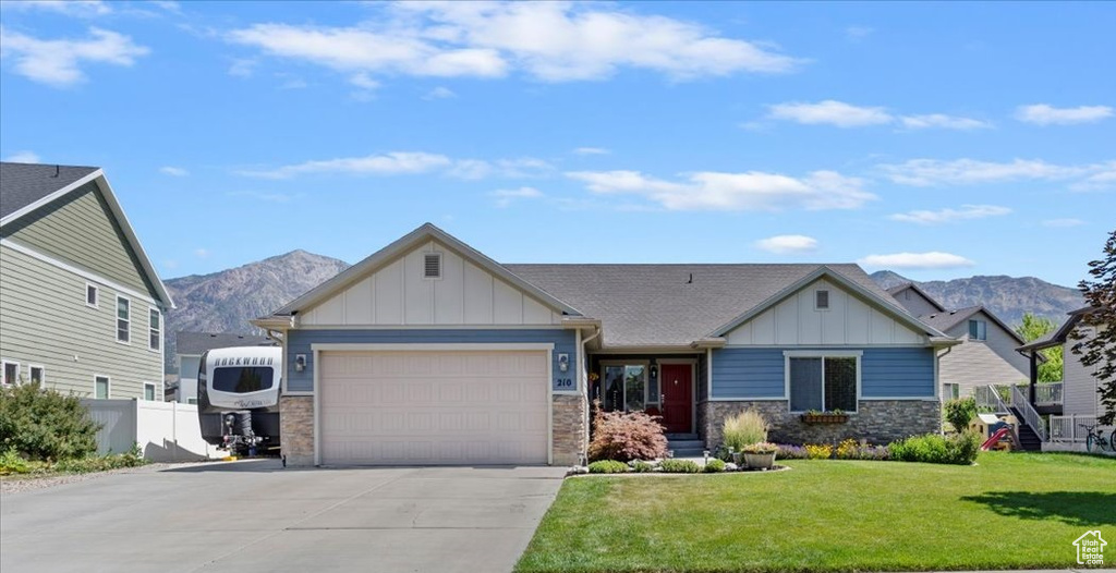 Craftsman inspired home with board and batten siding, driveway, a mountain view, a garage, and stone siding